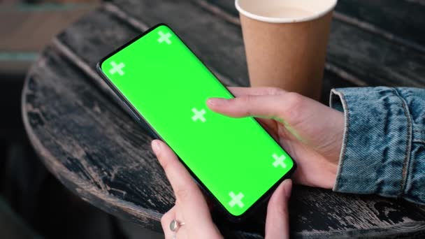 Lviv, Ukraine - May 6, 2022: Close up of a womans hand holding a mobile telephone with a vertical green screen outside chroma key smartphone technology cell phone street touch message display hand — Stock video