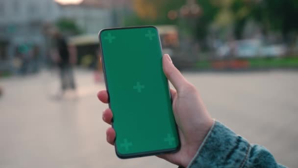 Lviv, Ukraine - May 6, 2022: Close up of a womans hand holding a mobile telephone with a vertical green screen outside chroma key smartphone technology cell phone street touch message display hand — Stock video