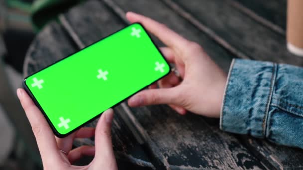 Lviv, Ukraine - May 6, 2022: Close up Horizontal hands holding smartphone with green screen outside. Green screen mobile phone with chroma key. Perfect for product placement — Video