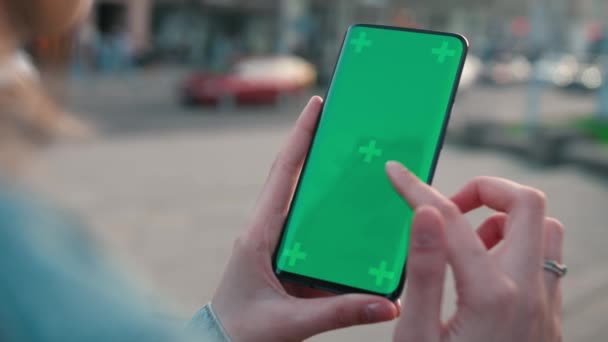 Lviv, Ukraine - May 6, 2022: Close up of a womans hand scrolling a mobile telephone with a vertical green screen in car chroma key smartphone technology cell phone street touch message display hand — Stock video