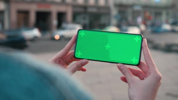 Lviv, Ukraine - May 6, 2022: Close up Horizontal hands holding smartphone with green screen outside. Green screen mobile phone with chroma key. Perfect for product placement — Stock video