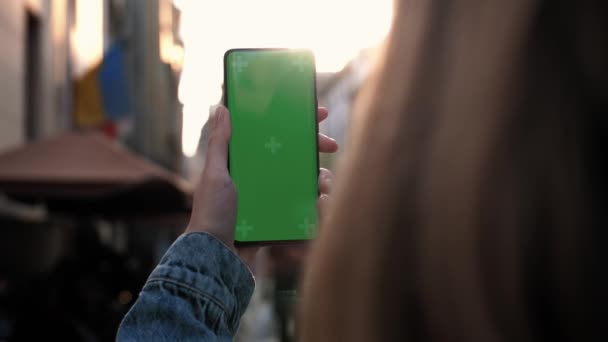 Lviv, Ucrania - 6 de mayo de 2022: Acercamiento de una mano de mujer sosteniendo un teléfono móvil con una pantalla verde vertical fuera de la tecnología de teléfonos inteligentes croma teléfono celular mano de visualización de mensaje táctil de calle — Vídeos de Stock