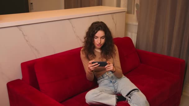 Young women listening to music and dancing energetic and rhythm at couch. Attractive Asian girl looking at the smart phone sitting in the living room spending leisure time at home. — Αρχείο Βίντεο