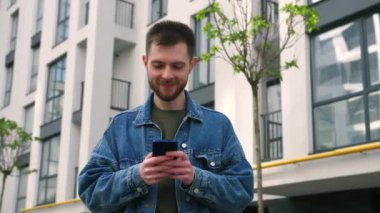 Cep telefonu kullanan yakışıklı, sakallı, beyaz adam. Mesaj atan genç bir adam, Ofis Bölgesi 'nde akıllı telefonunu aldatıyor. İş için. Sosyal ağ. - İnsanlar. Uygulamalar. Yüksek kalite 4k görüntü