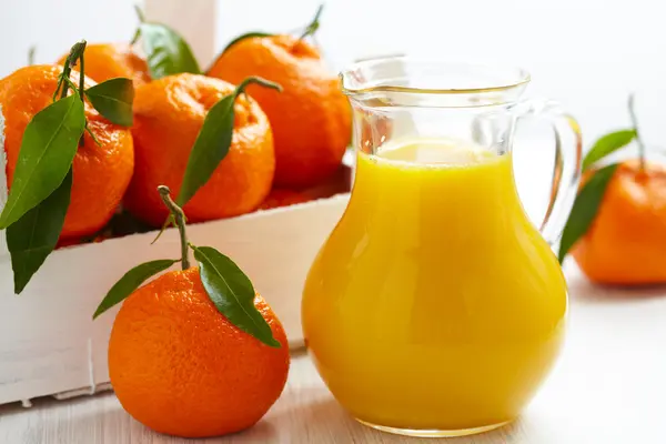 Orange juice in pitcher and tangerines — Stock Photo, Image