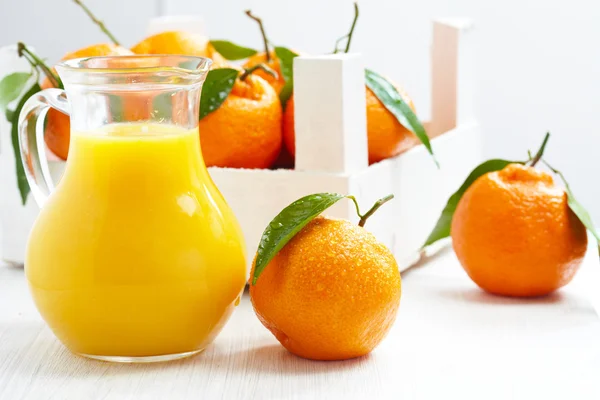 Orange juice in pitcher and tangerines — Stock Photo, Image