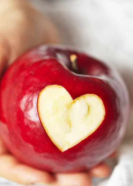 Χέρι που κρατά το κόκκινο μήλο με καρδιά — Φωτογραφία Αρχείου