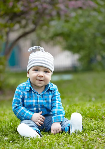 Baby boy sitting on green grass — Stock Photo, Image