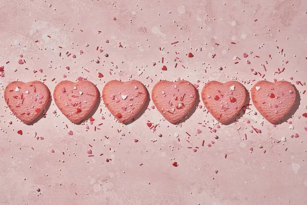 Galletas decoradas en forma de corazón sobre fondo rosa —  Fotos de Stock