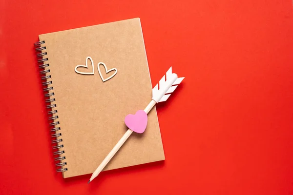 Blank notepad, pensil and wooden hearts on red background for Valentines Day — Photo