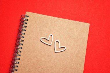 Blank notepad, pensil and wooden hearts on red background for Valentines Day