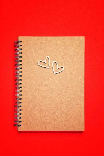 Κενό σημειωματάριο, pensil και ξύλινες καρδιές σε κόκκινο φόντο για την Ημέρα του Αγίου Βαλεντίνου — Φωτογραφία Αρχείου