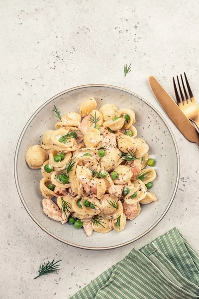 Orecchiette pasta with smoked salmon, green peas and creamy sauce Stockbild