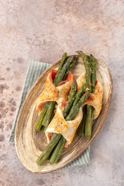 Baked green asparagus with ham and cheese in puff pastry