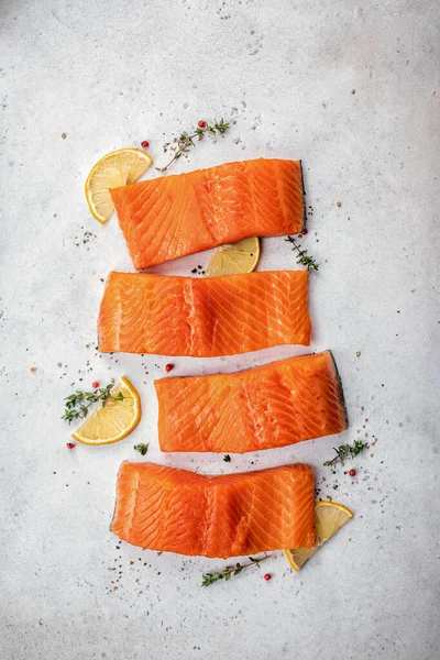 Somon balığı. Pişirme malzemeleri, otlar ve limonlu taze çiğ somon balığı filetosu.