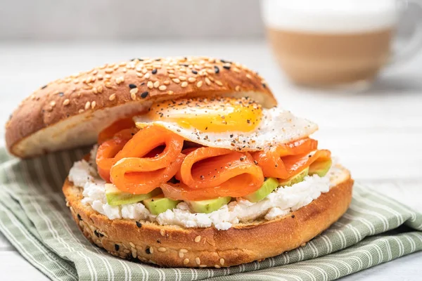 Panino al bagel con salmone, crema di formaggio, avocado e uova. — Foto Stock