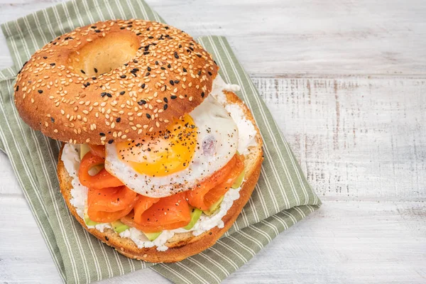 Panino al bagel con salmone, crema di formaggio, avocado e uova. — Foto Stock