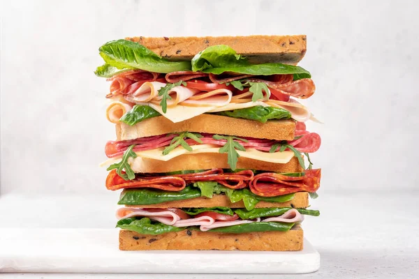 Duża smaczna kanapka z szynką, salami, sałatką, serem i pomidorami Obraz Stockowy