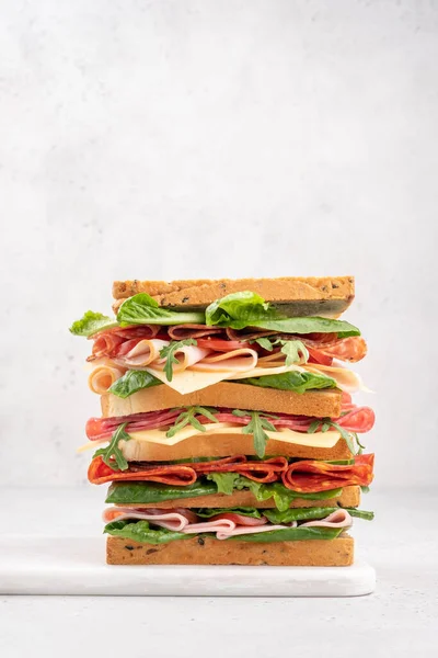 Grande sanduíche saboroso com presunto, salame, salada, queijo e tomate — Fotografia de Stock