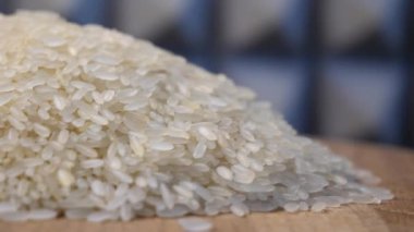 Dönen ahşap bir yüzey üzerinde bir pirinç taneleri yığını yatıyor. Beyaz pirinç, makro..
