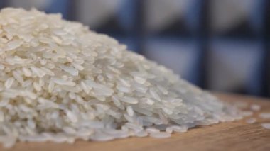 Dönen ahşap bir yüzey üzerinde bir pirinç taneleri yığını yatıyor. Beyaz pirinç, makro..