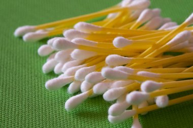 Yeşil arka planda çok sayıda pamuk çubuğu, yakın çekim. Pamuklu çubuklar ya da pamuk tomurcukları. Genelde kulak temizliği için kullanılır..