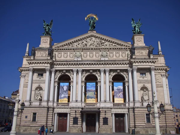 Lviv, Ukrayna, 25 Mart 2022. Güneşli bir günde Solomiya Krushelnytska Lviv Devlet Opera ve Bale Akademik Tiyatrosu. Tiyatronun ön cephesinde posterler. Sokaktaki insanlar.