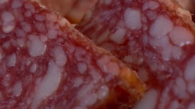 Birkaç parça sosis yakın plan. Salam, tam kare. Tam HD video, seçici odaklanma. Sosisi dilimliyorum. Çiğ füme sosis ürünü..