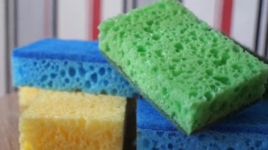 Multi-colored washcloths for washing dishes and cleaning on a rotating surface, macro video. Green, blue and yellow sponges. Highly detailed 4k video. Household items.