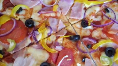 Zeytinli, domatesli ve jambonlu pizza. Kapalı çekimli video. Dönen pizza, tam kare görüntü. İtalyan yemeği, makro..