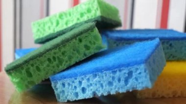 Multi-colored washcloths for washing dishes and cleaning on a rotating surface, macro video. Green, blue and yellow sponges. Highly detailed 4k video.