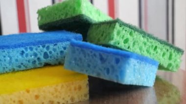 Multi-colored washcloths for washing dishes and cleaning on a rotating surface, macro video. Green, blue and yellow sponges, 4k  video.