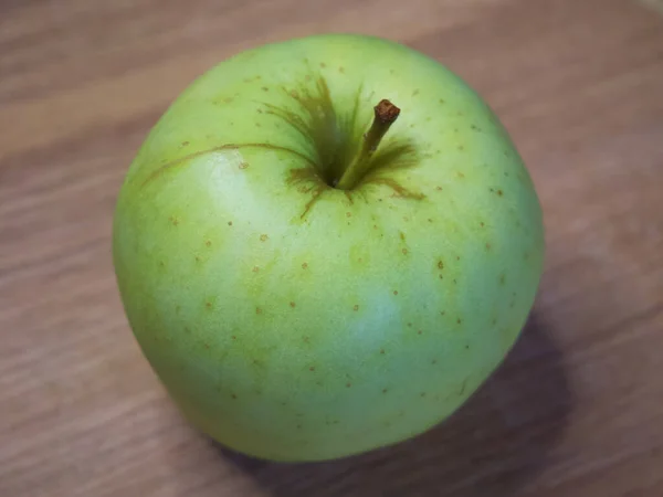 雷尼特西米连科是一个古老的苹果品种 果肉嫩 带有淡淡的酸味 一个绿色的苹果放在木制桌面上 — 图库照片