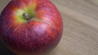 One big red apple rotates on a wooden surface, close-up video. 4k video with an apple and a place for text.
