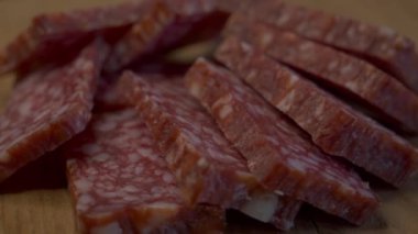 Dönen ahşap bir yüzey üzerinde dikdörtgen salam parçaları. Sosis yakın plan. 4k video.