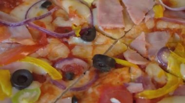 Zeytinli, domatesli ve jambonlu pizza. Kapalı çekimli video. Döndürme.
