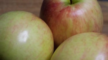 Dönen bir yüzeyde üç büyük güzel elma. Makro video. Meyve yakın plan..