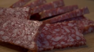 Dönen ahşap bir yüzey üzerinde dikdörtgen salam parçaları. Sosis yakın plan..