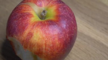 Gala 'nın büyük elması ahşap bir yüzeyde, 4k makro video çözünürlüğünde. Isırılmış elma döner. Metin için bir yer, kopyalama alanı.