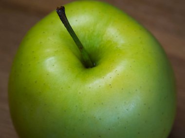 Reinette Simirenko antika bir elma çeşididir. Meyvenin yumuşak, gevrek, yeşilimsi, asit altı tadı olan beyaz eti var. Ahşap bir masanın üstünde yeşil bir elma, yakın plan..