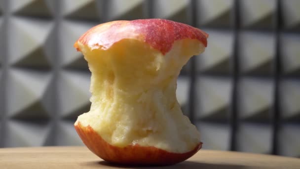 回転する木製の表面上の1つの赤いリンゴのコア 4Kクローズアップビデオ サイドビュー — ストック動画