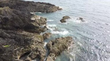 Deniz kıyısındaki kayalar. Jeolojik oluşumlar. Suyun üzerinde güneş parlıyor..