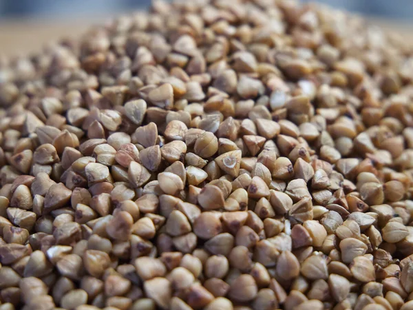 Organic buckwheat groats macro background. Roasted dry buckwheat grains texture close-up. Wholegrain buckwheat seeds for gluten free diet, vegetarian food and dietary fiber concepts.