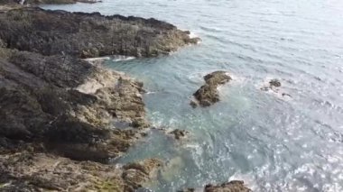 Deniz kıyısındaki kayalar. Jeolojik oluşumlar. Suyun üzerinde güneş parlıyor. Deniz Burnu.