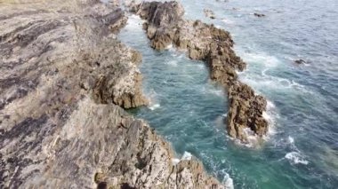 Turkuaz dalgalar bir kayanın üzerinde kırılır. Güzel deniz manzarası. Beyaz deniz köpüğü.