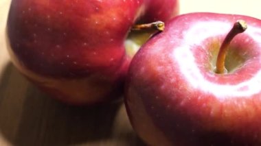 Highlights on the peel of red apples. Large ripe apples close-up, rotation. Macro video in 4k resolution. Fruit on a wooden background.