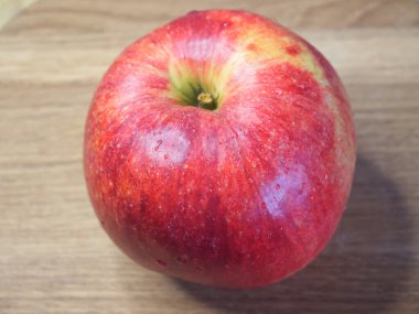Ahşap bir masada büyük kırmızı bir elma, yakın çekim..