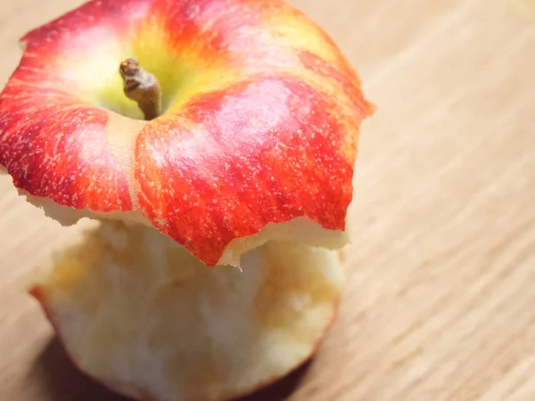 Red apple core on a wooden background. A bitten apple close-up.