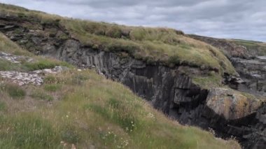 Atlantik 'in kayalık kıyıları. Deniz kıyısında büyük taşlar. Bulutlu gökyüzü.