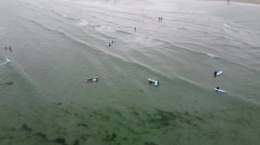 West Cork, Ireland, July 3, 2022. Surfing instructors teach beginners. People with surfboards on the sea. Tourists are engaged in water sports. Beach holidays in the Nordic countries.